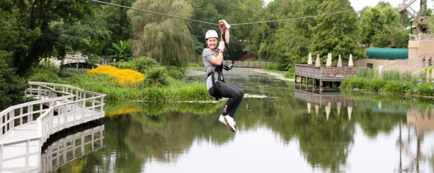 person smiling on zip line course over a pond in Kentucky