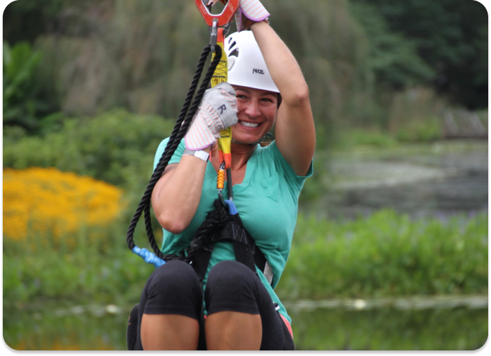 person smiling for the camera on a zip line course