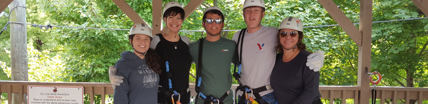 people posing for the camera before starting a zip line course
