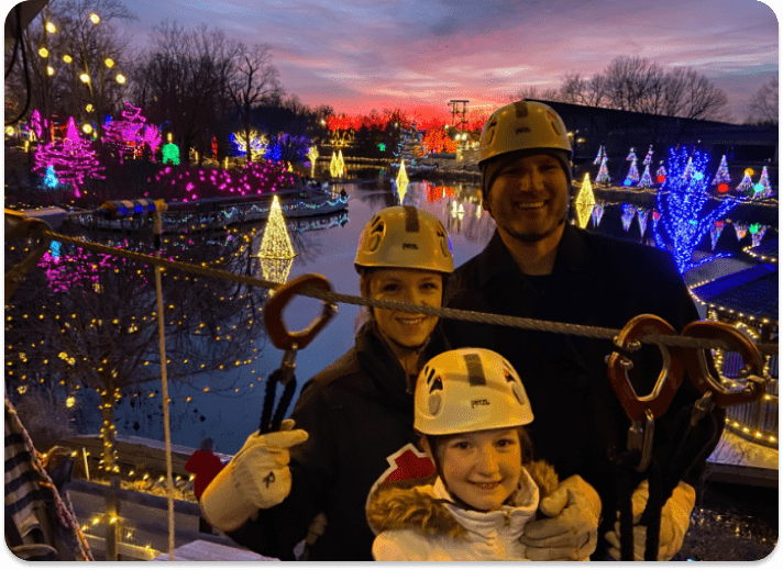 people posing for the camera at sunset on an aerial challenge course with Christmas Town in the background