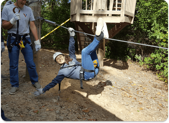 girl hanging on wire posing for the camera during team building activity