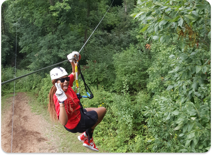 person posing for the camera while on a zip line course through the trees